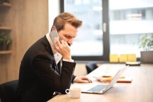 business person on the phone and using laptop